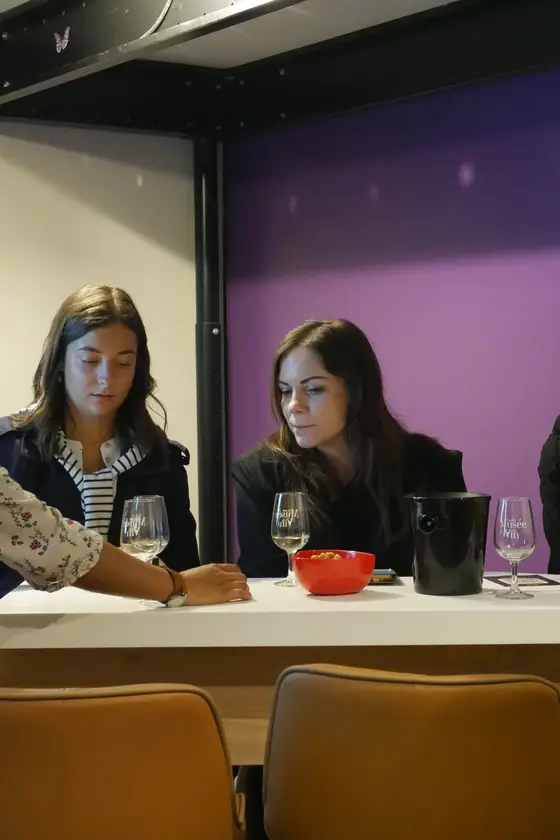 Groupe de participantes autour de la table lors d'une soirée Wine Break, murs violets